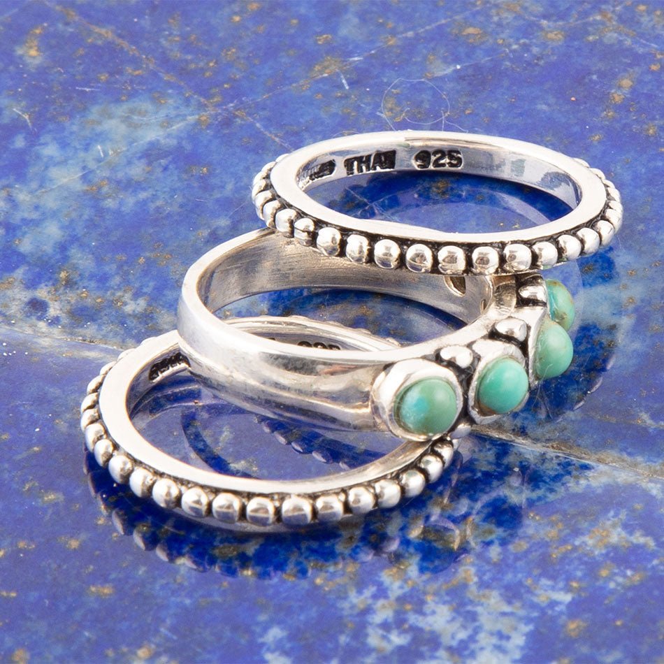 Three silver rings with turquoise stones on a blue textured background