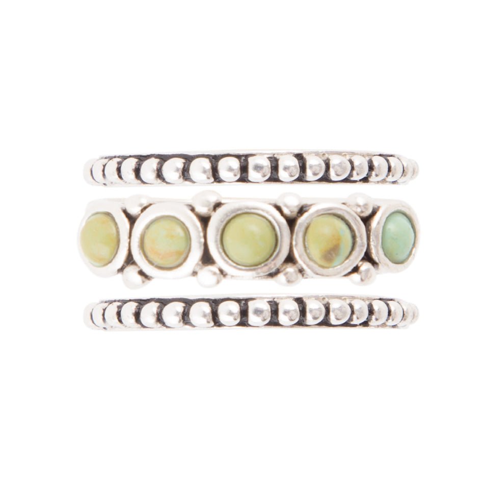 Set of three silver rings with green gemstones on a white background