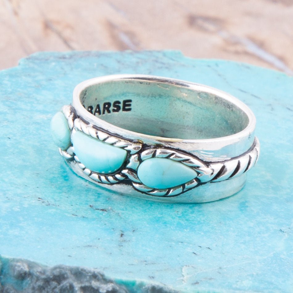 Silver ring with turquoise stones on a blue surface