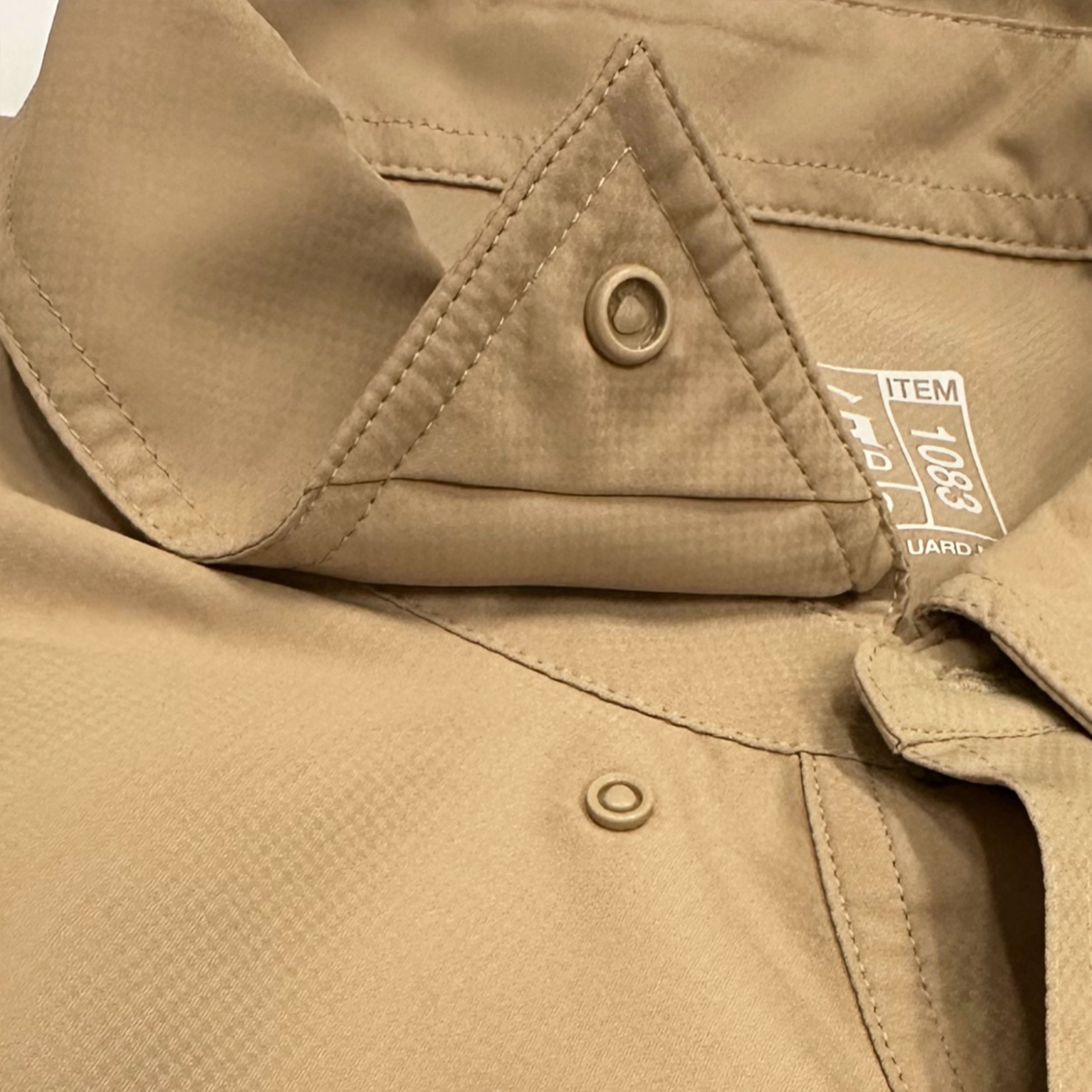 Close-up of a beige jacket with button details and a visible brand label.
