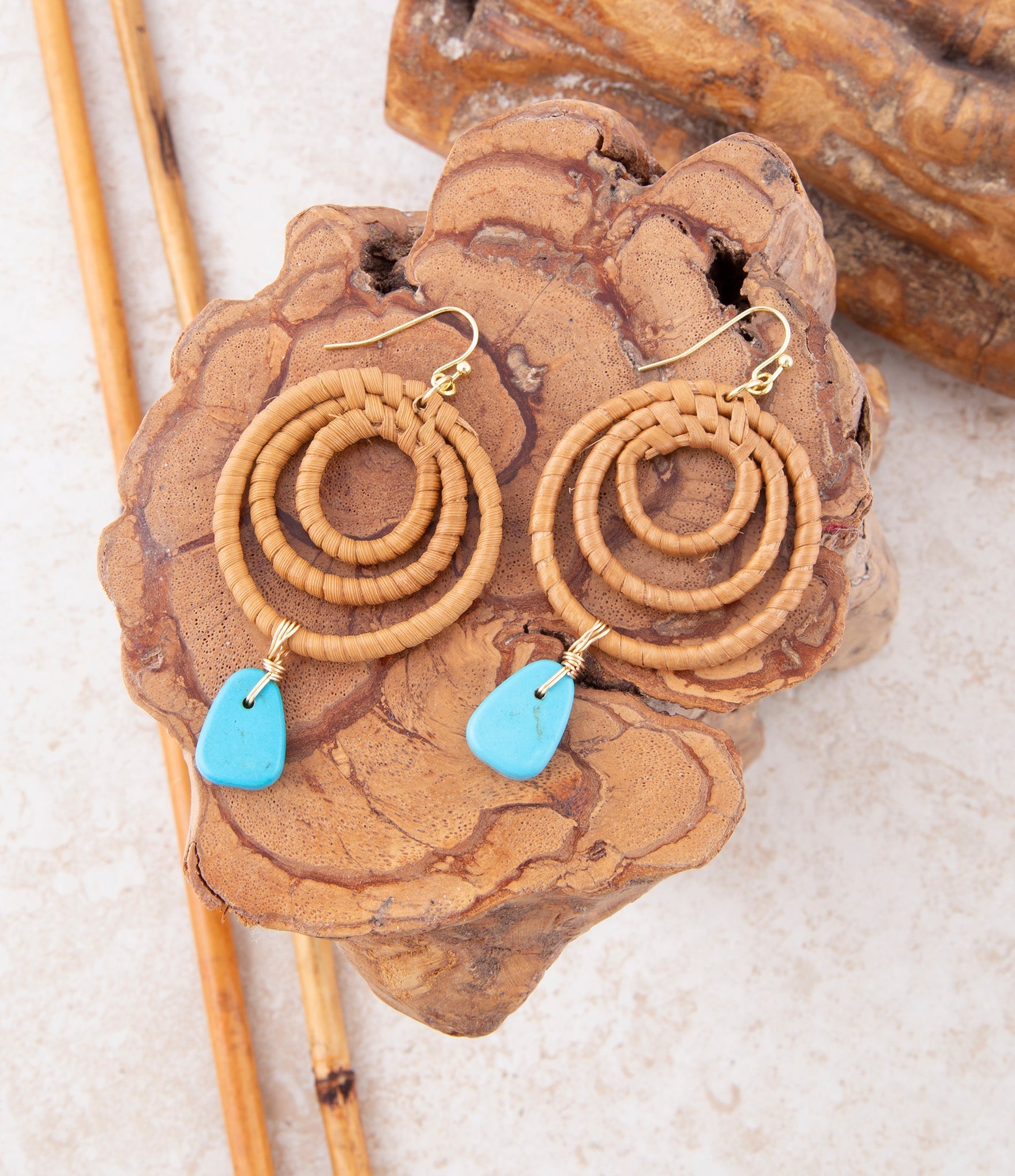 Pair of earrings with spiral design and turquoise stones on a wooden surface
