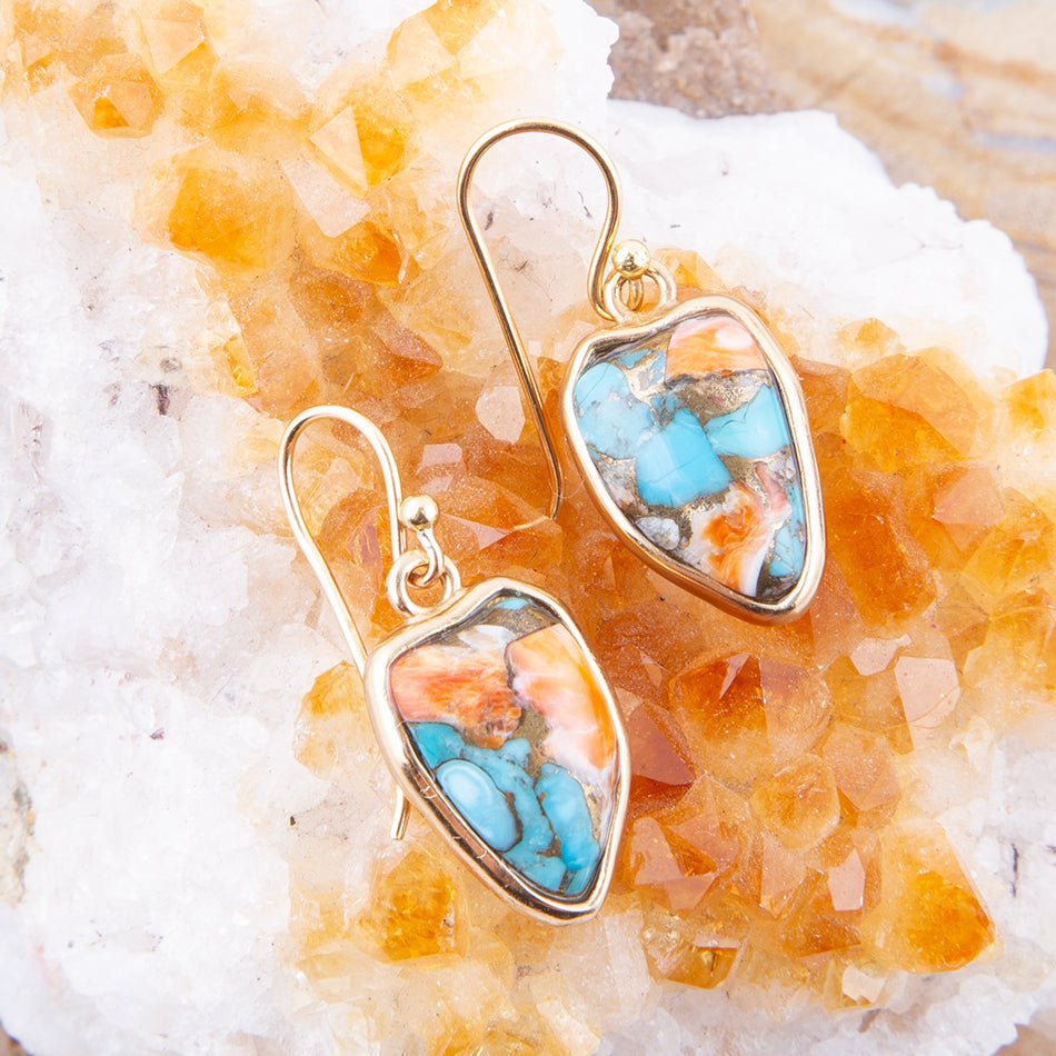 Gold earrings with turquoise stones on a crystal background