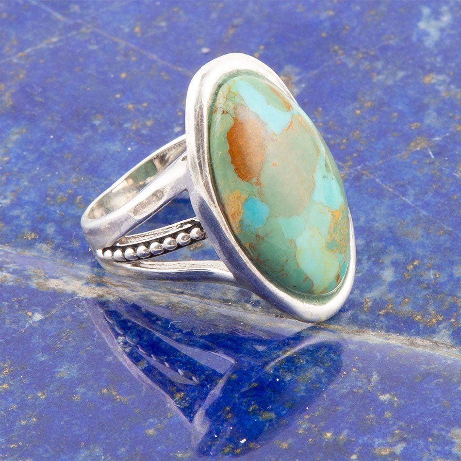 Silver ring with a turquoise stone on a blue textured background