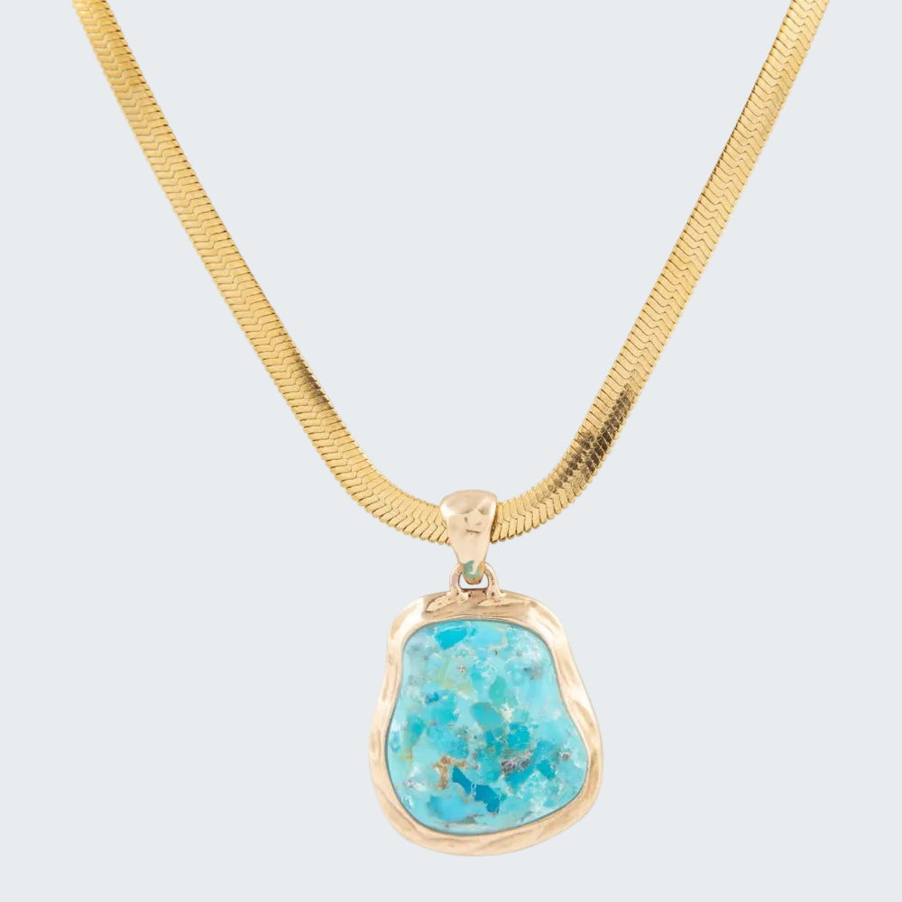 Turquoise pendant on a gold chain against a white background