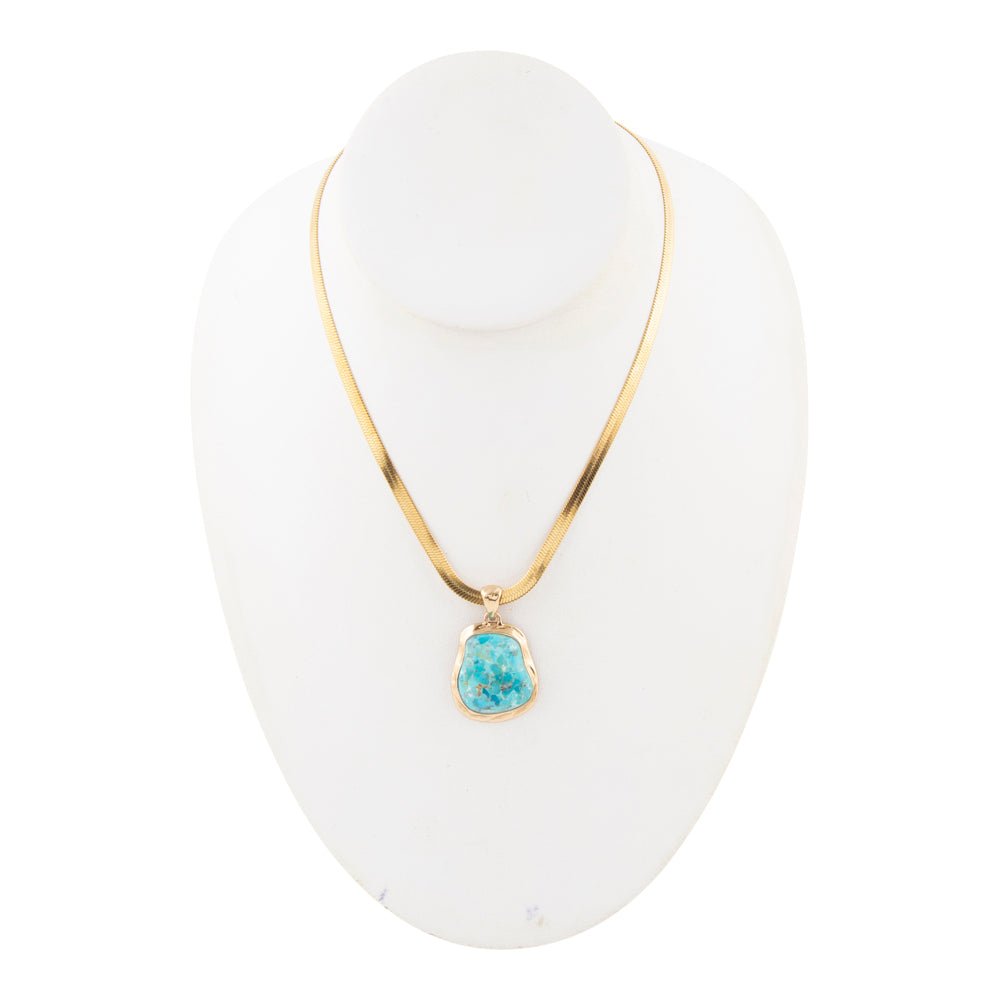 Gold necklace with a turquoise pendant on a white mannequin head.