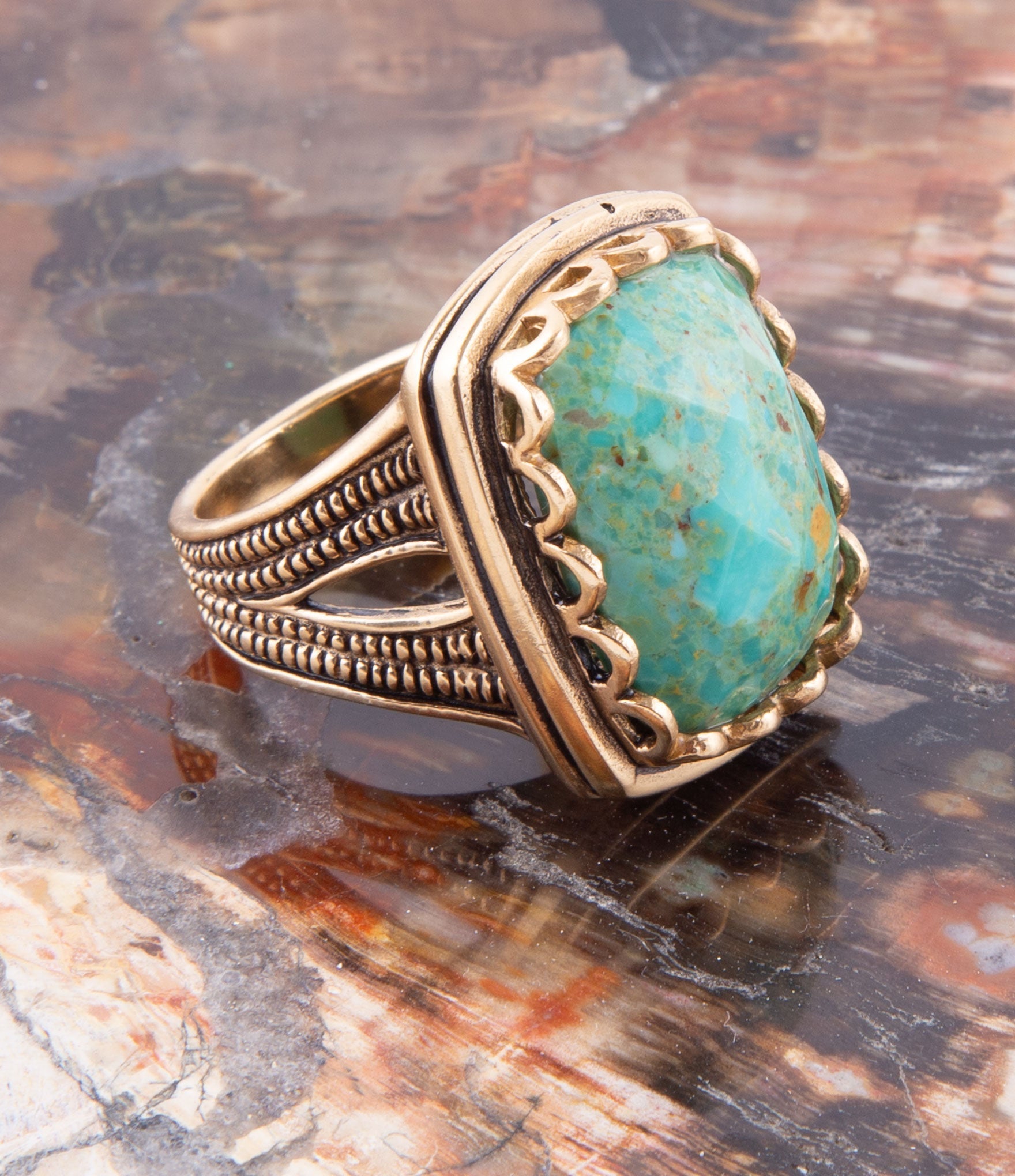Gold ring with a turquoise stone on a textured surface