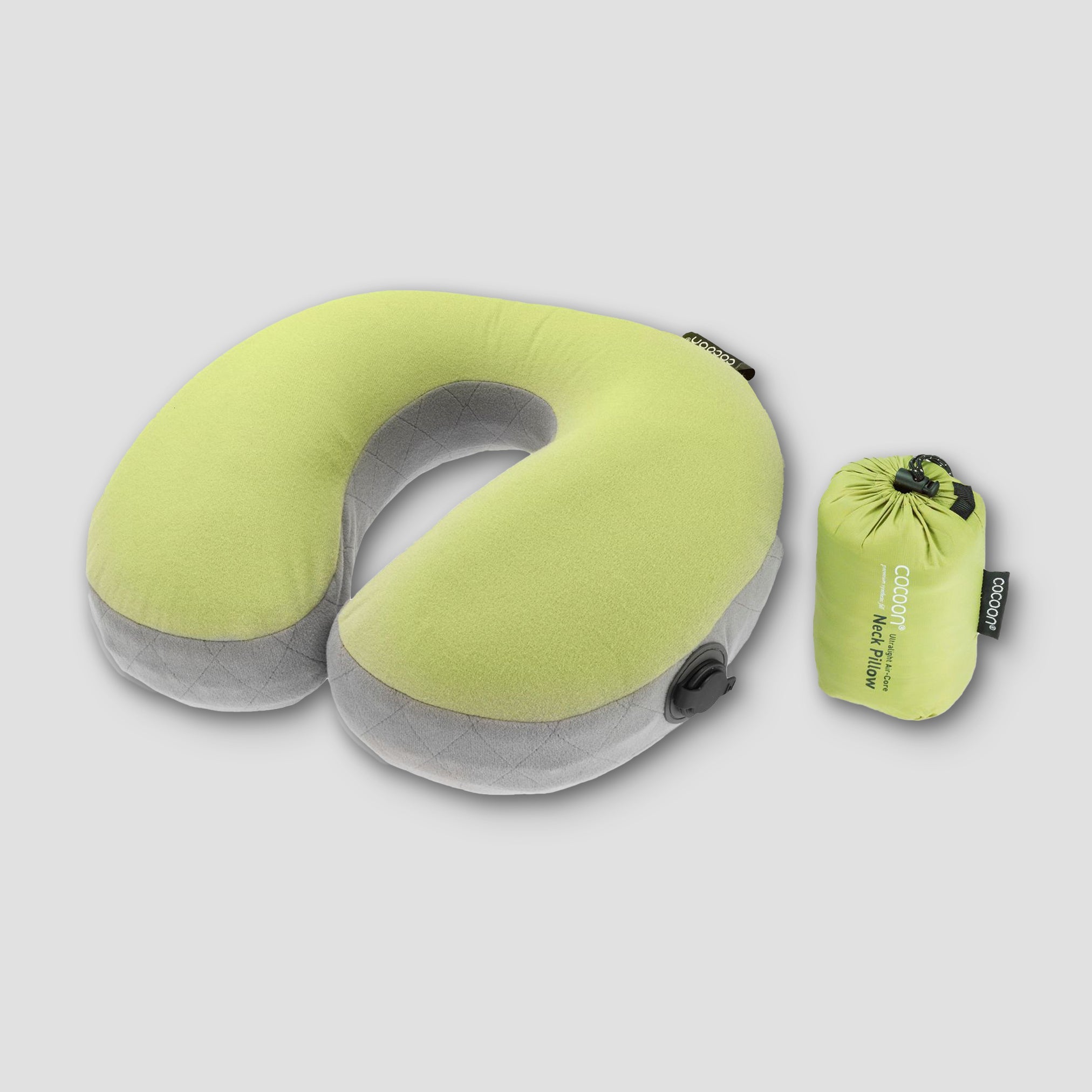 Green travel neck pillow with its packaging on a light gray background