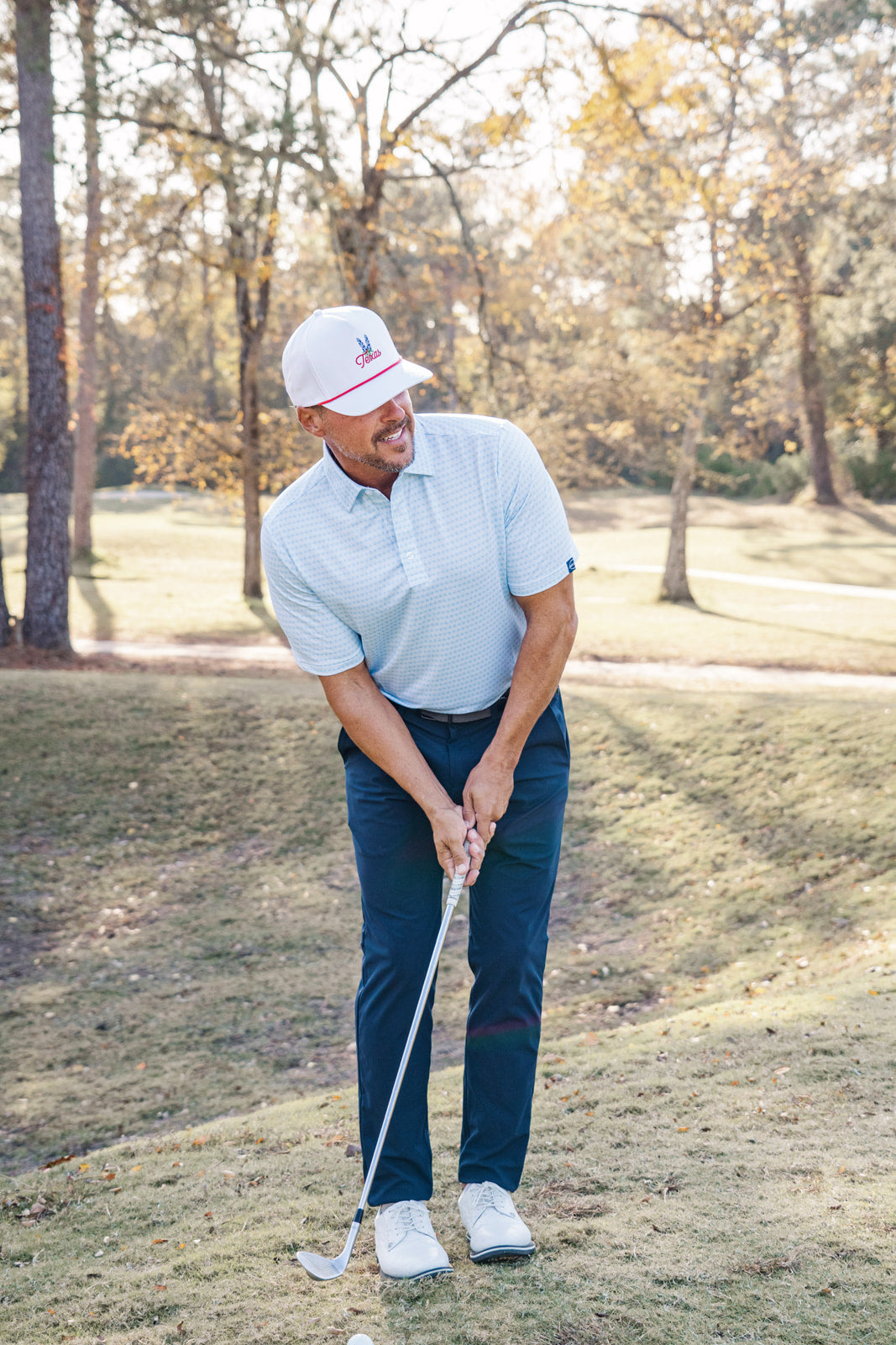 Man playing golf on a grassy course with trees in the background