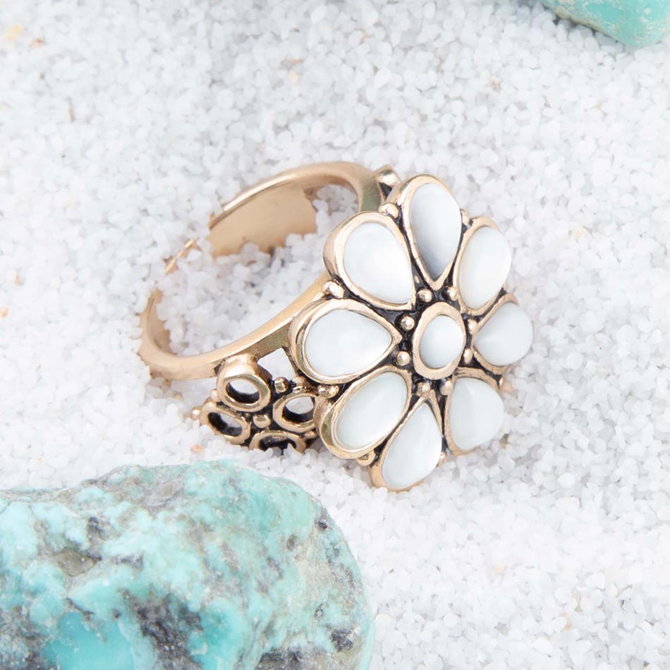 Gold ring with white stones on a sandy surface with turquoise stone