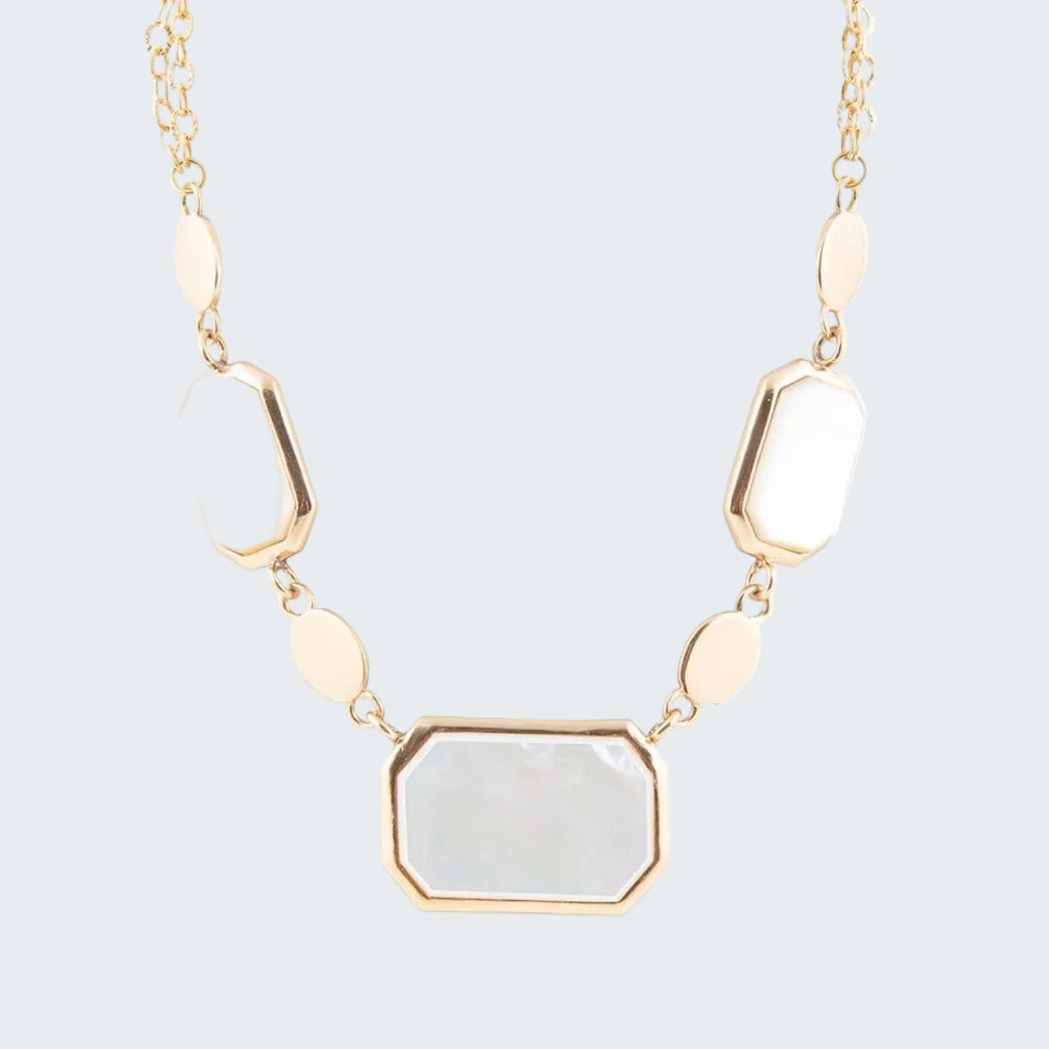 Necklace with gold chain and white stone pendants on a white background