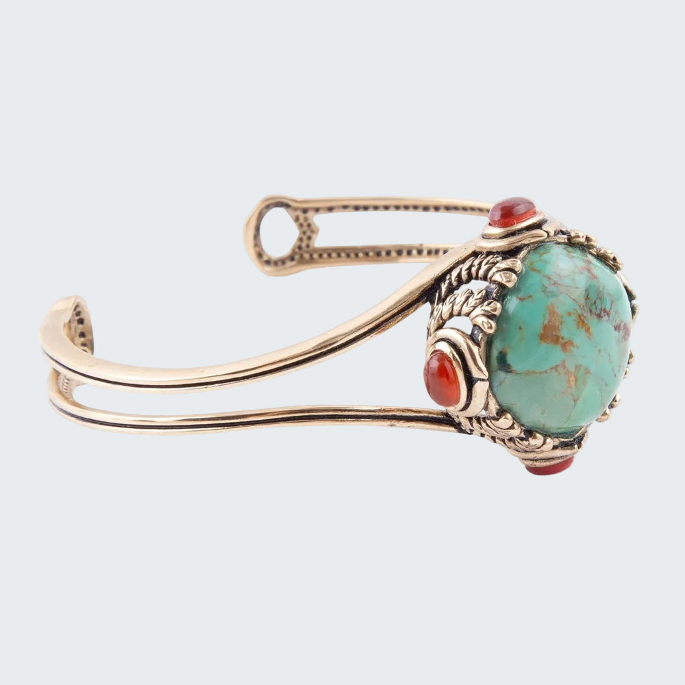 Gold bracelet with turquoise and red stone on a white background