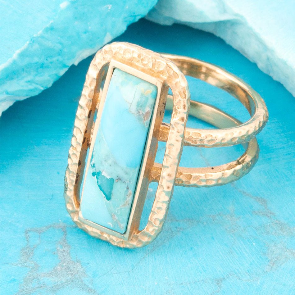Gold ring with turquoise stone on a blue background