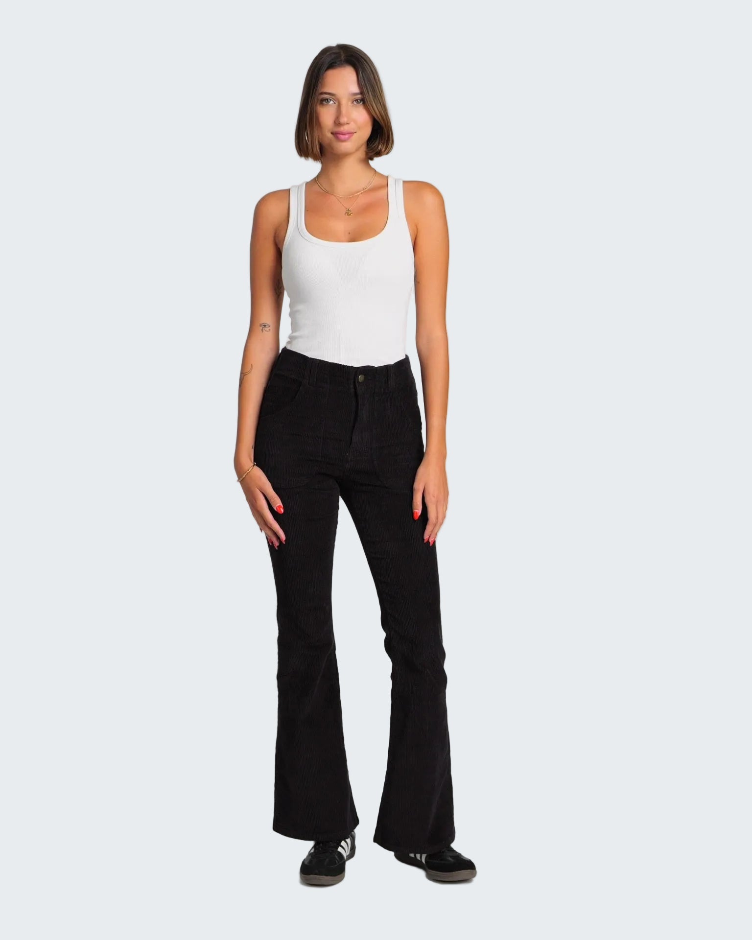 Woman wearing a white tank top and black flared pants on a white background