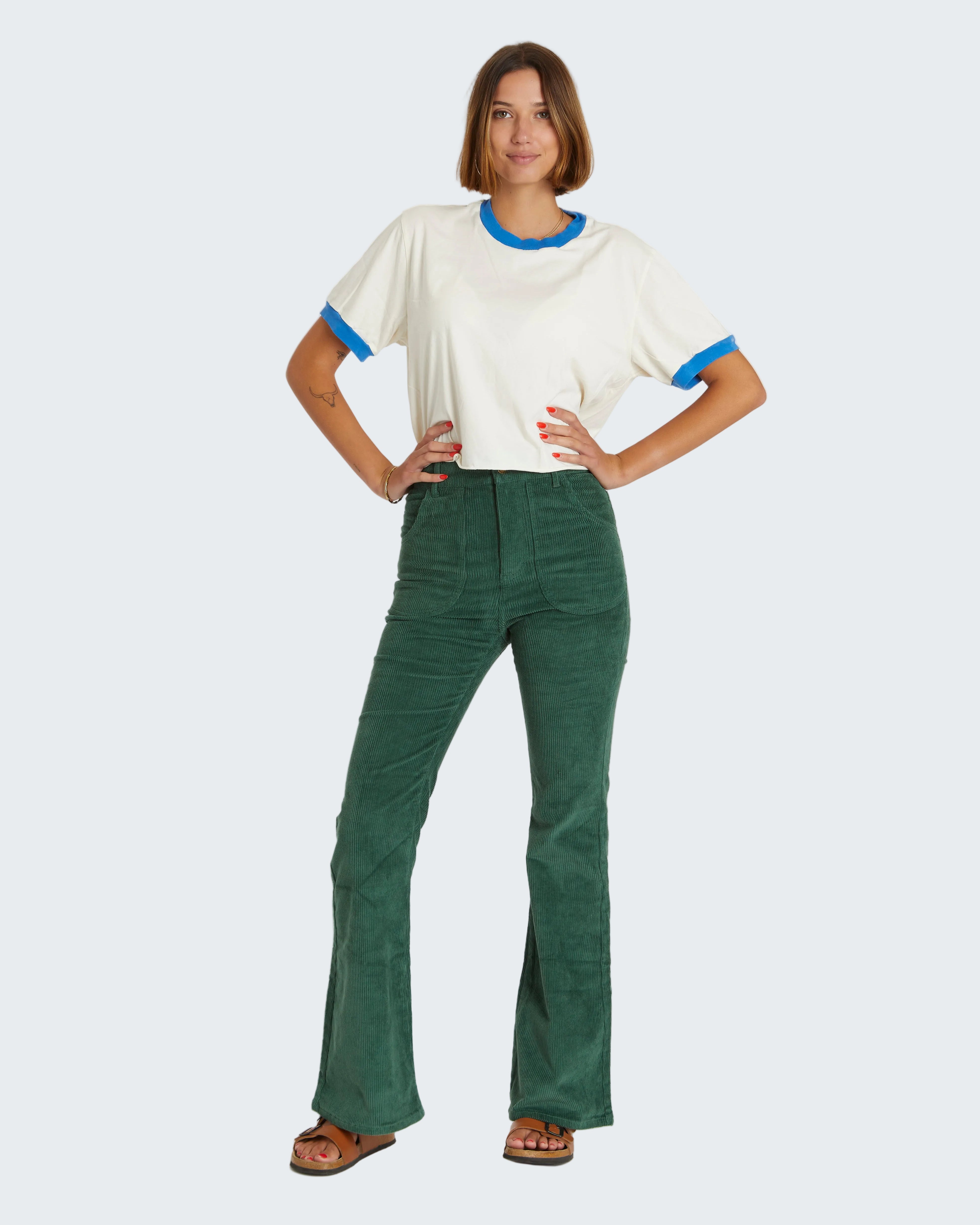 Woman wearing a white t-shirt with blue trim and green pants on a white background