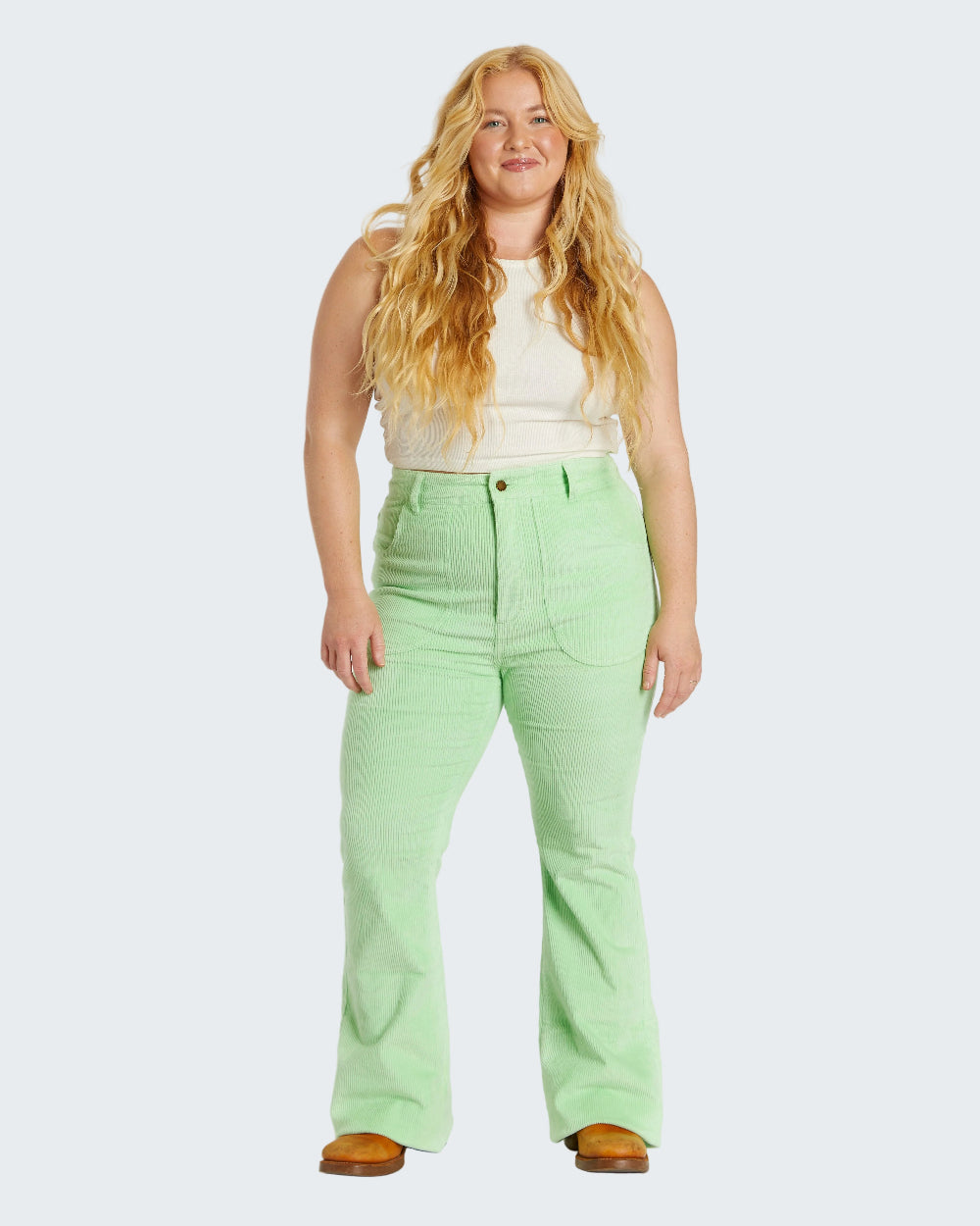 Woman wearing light green pants and a white top on a white background