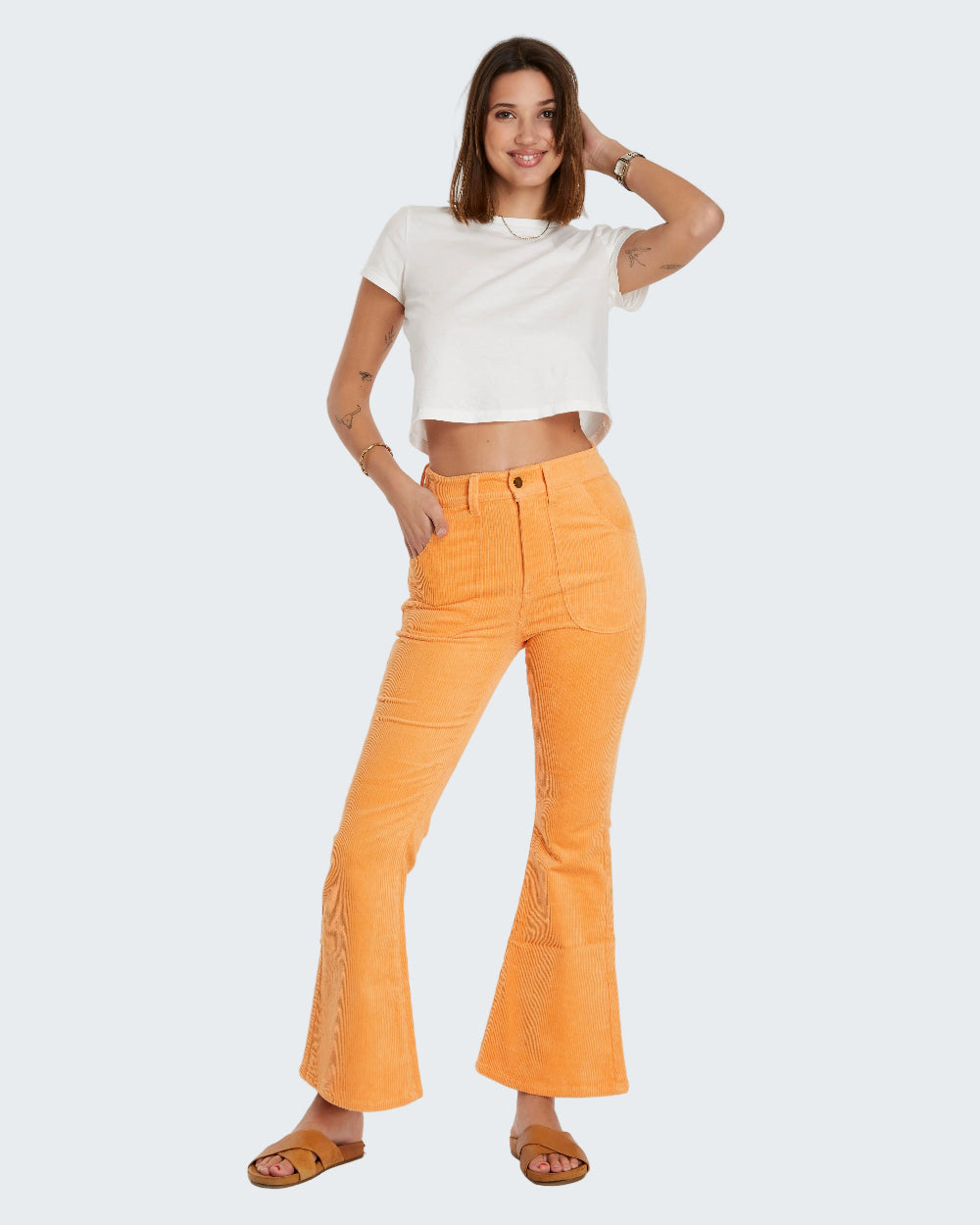 Woman wearing a white top and orange pants on a white background