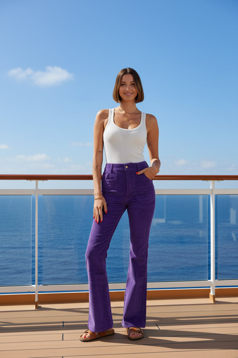 Woman wearing purple flared pants and a white tank top on a white background