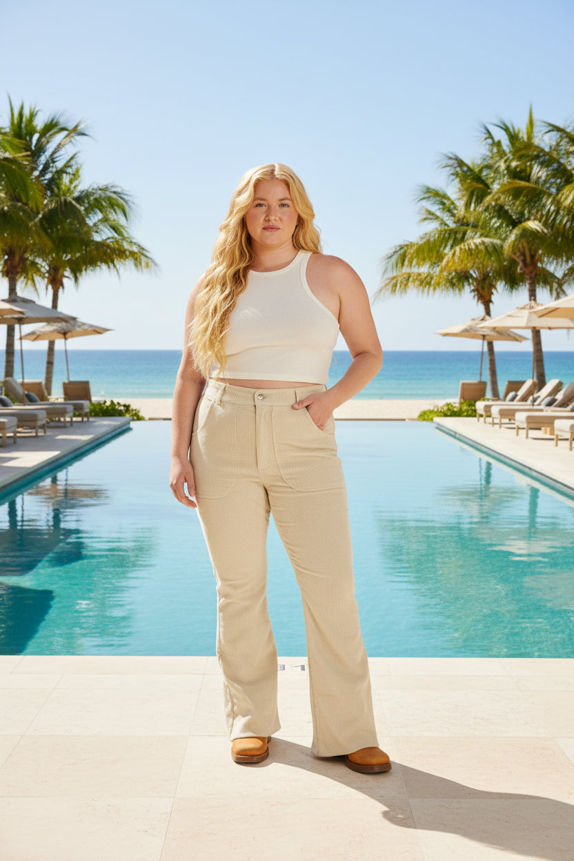 Woman wearing a white sleeveless top and beige pants on a white background