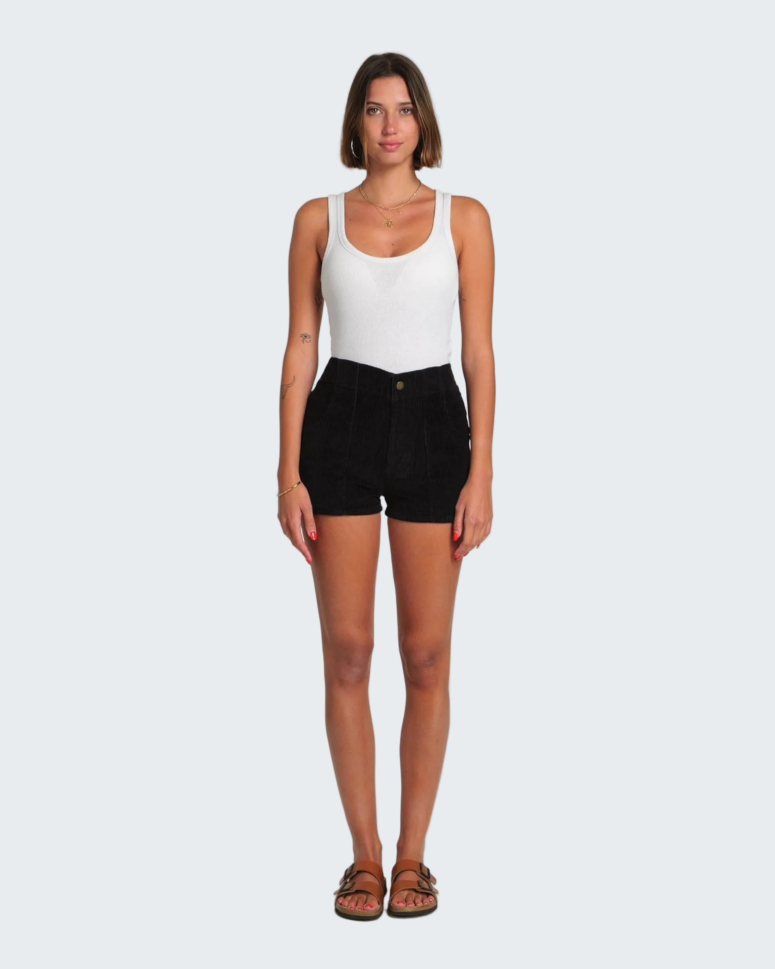 Woman wearing a white tank top and black shorts on a white background