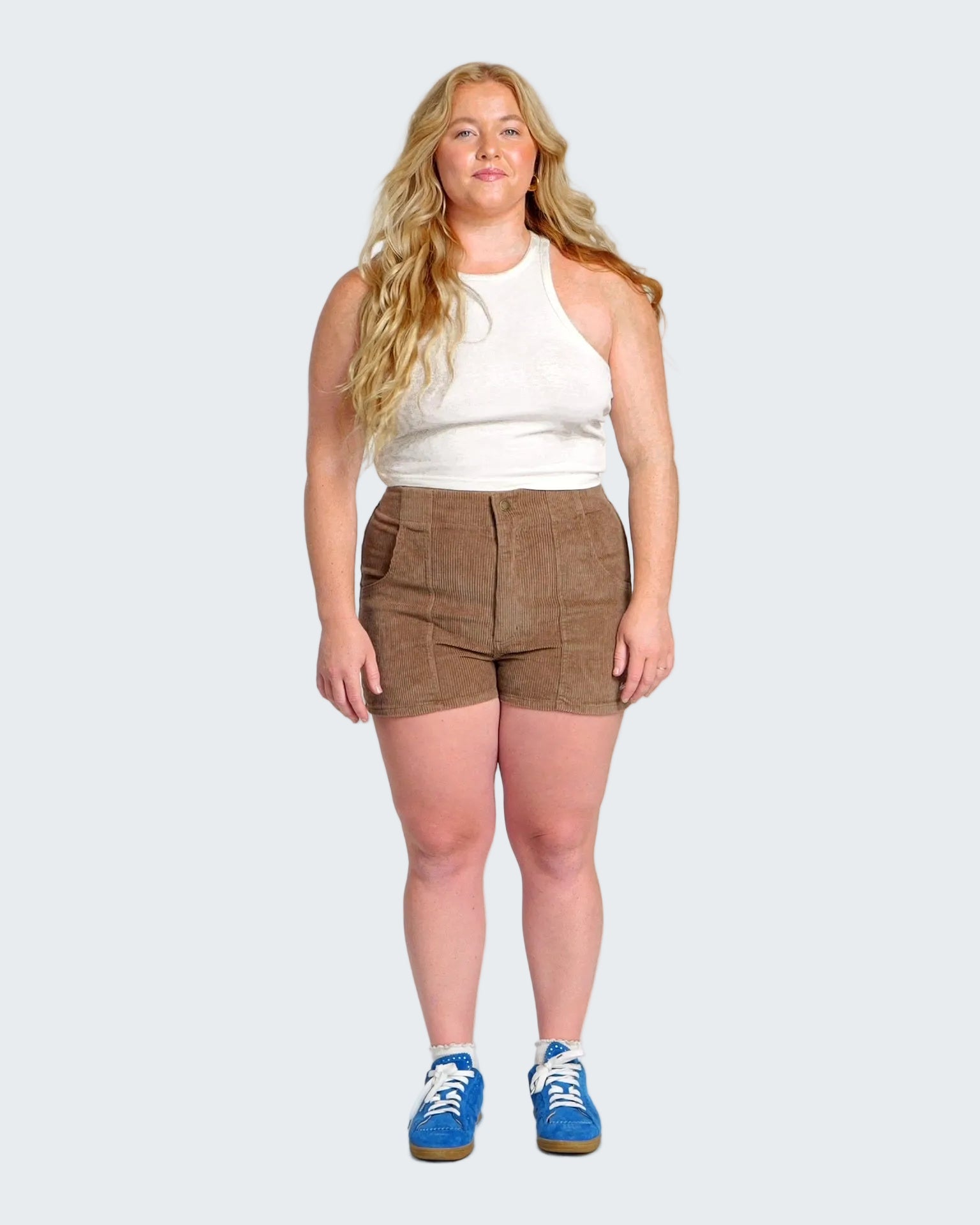 Woman wearing a white top and brown shorts on a white background