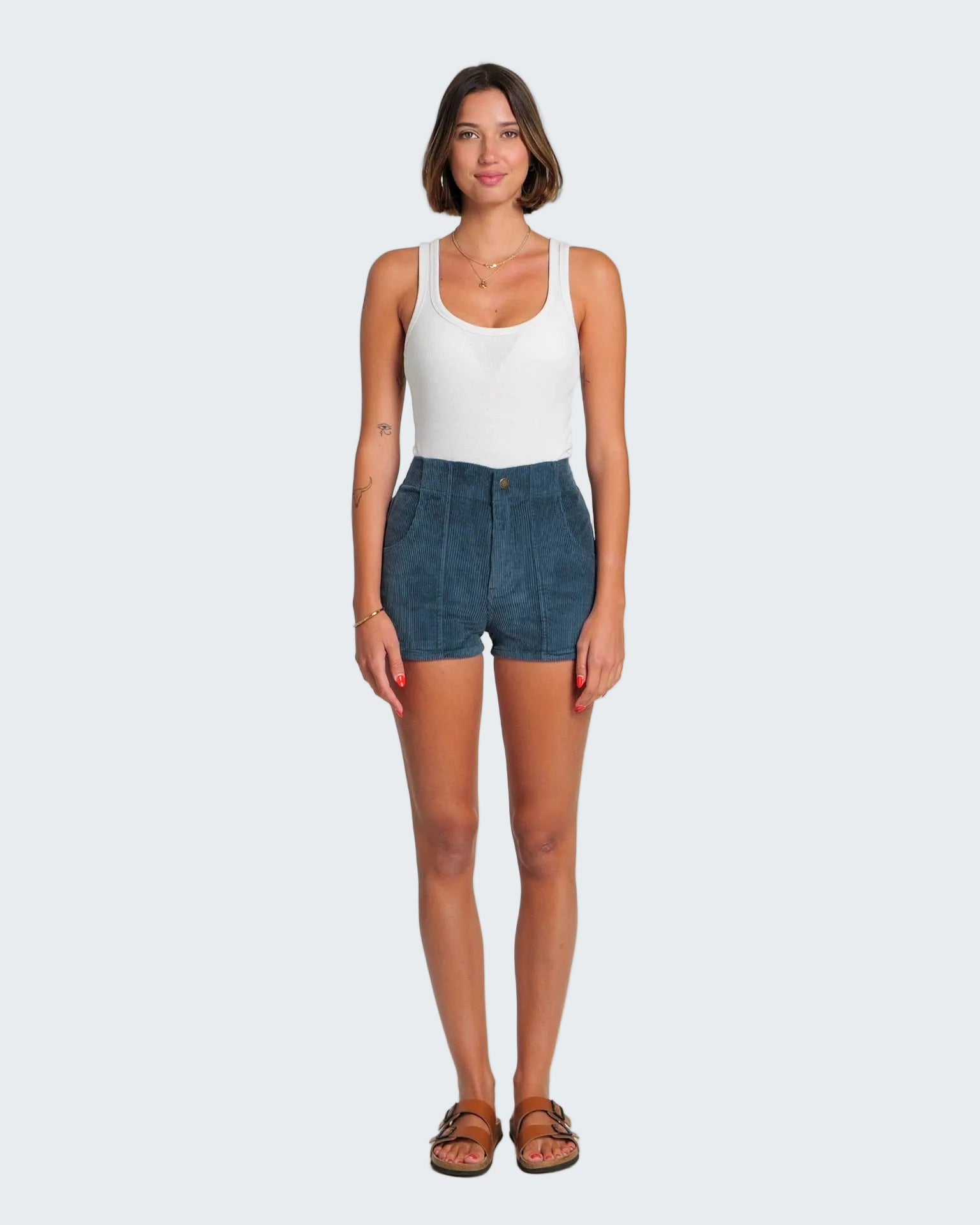 Woman wearing a white tank top and blue denim shorts on a white background
