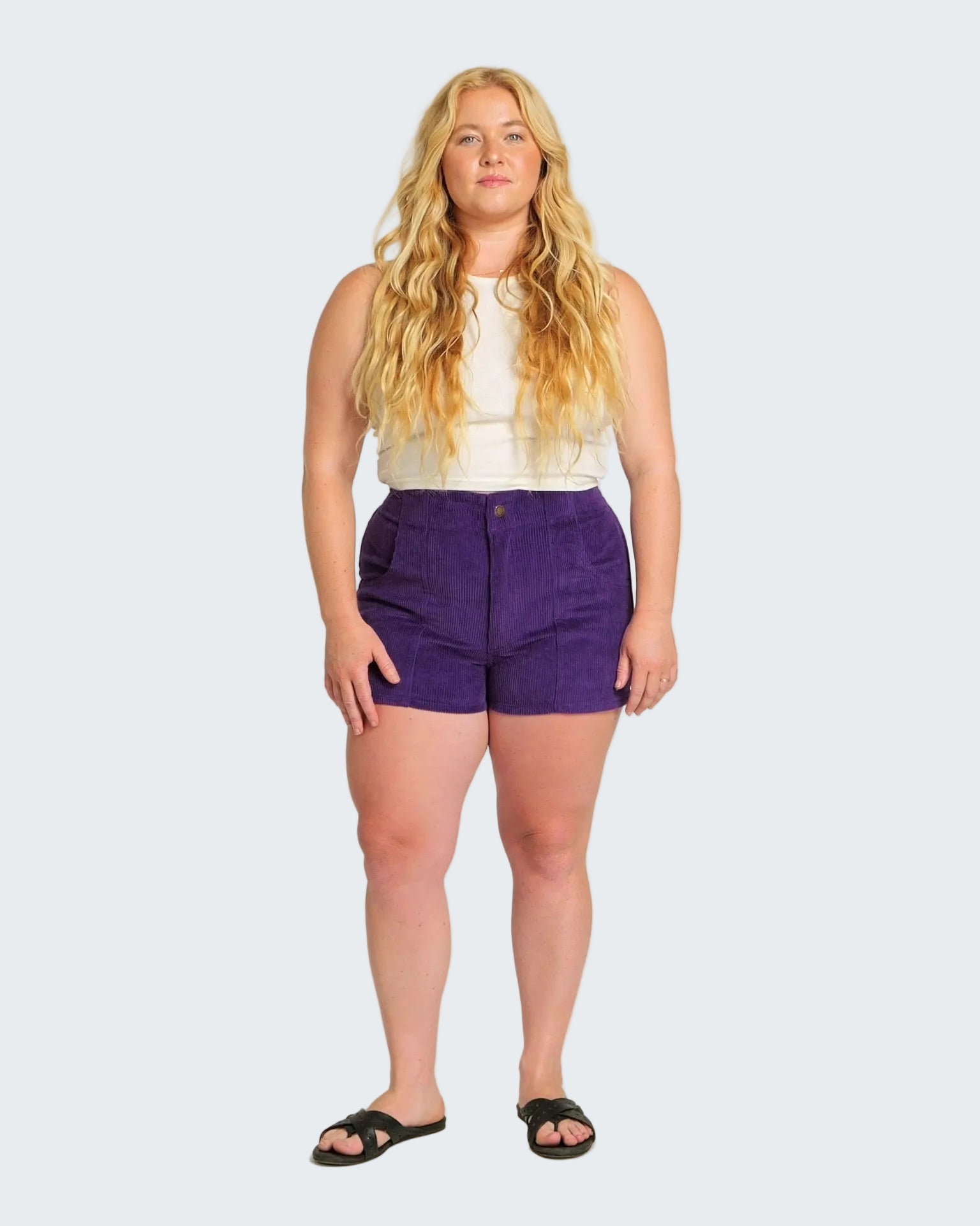 Woman wearing a white top and purple shorts on a white background