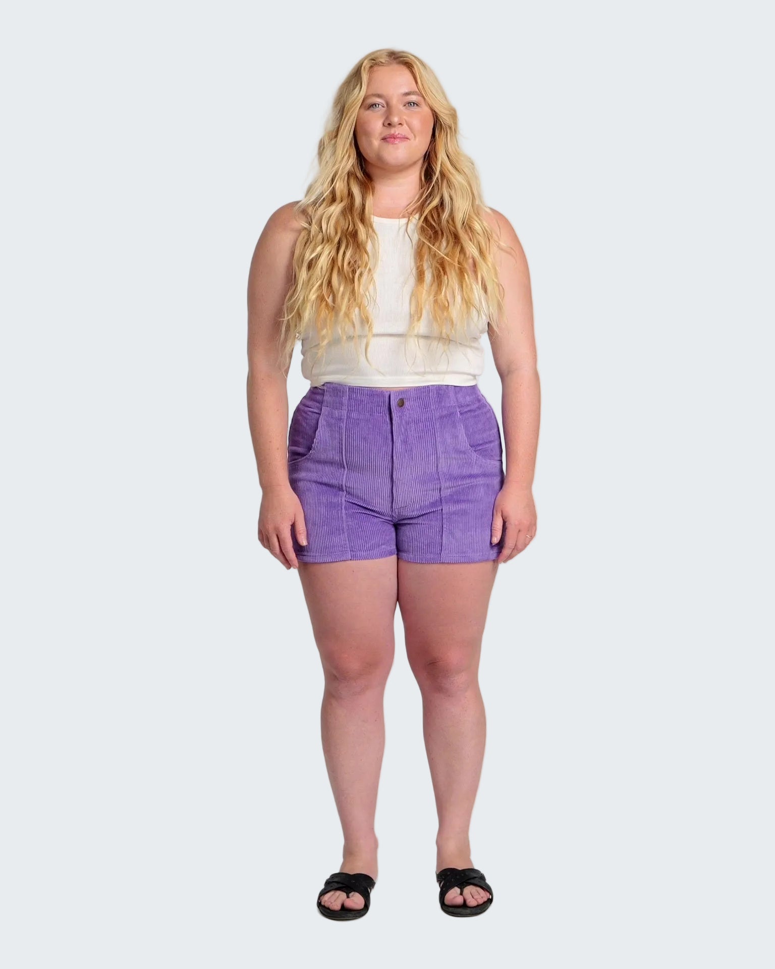 Woman wearing a white top and purple shorts on a white background