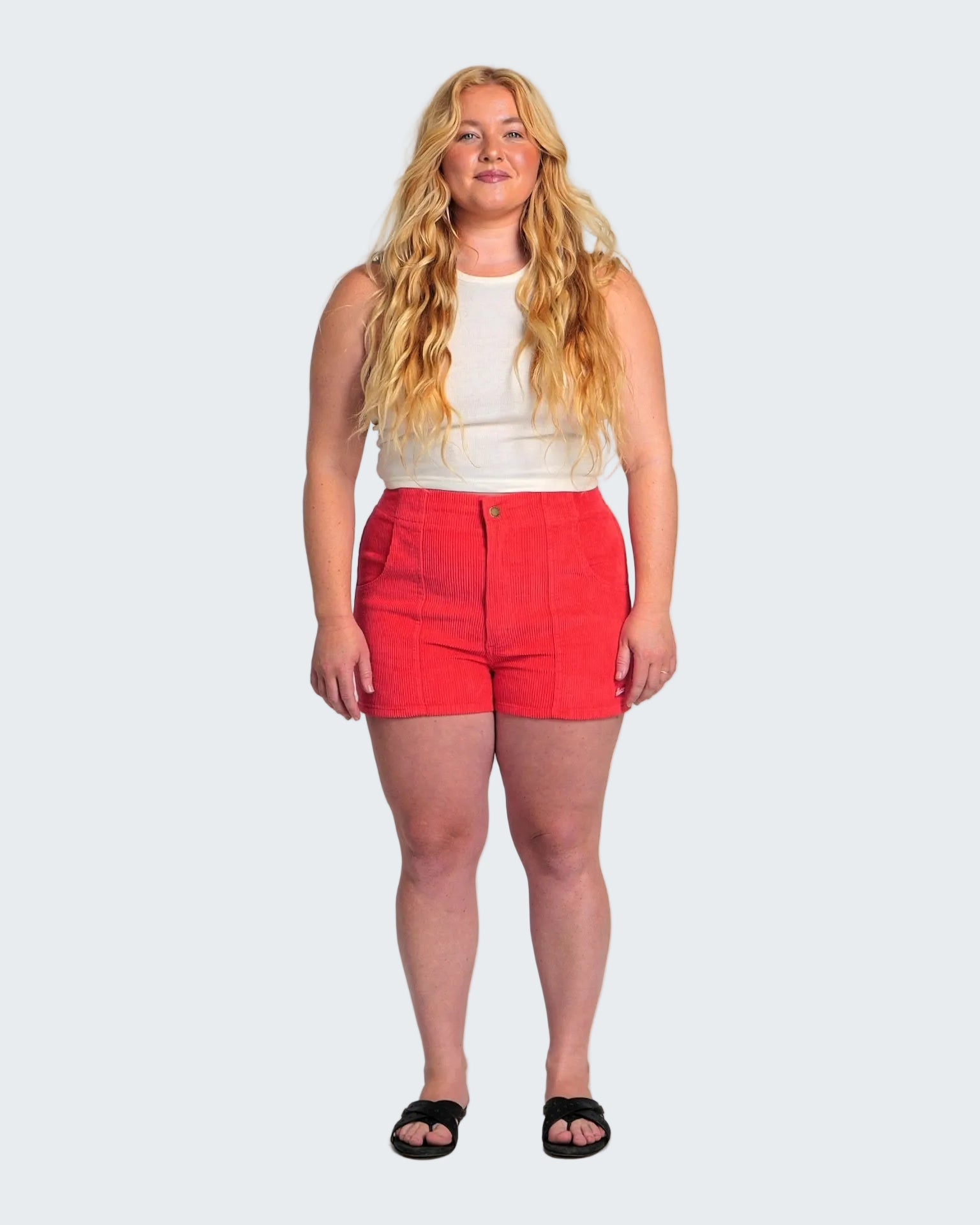 Woman wearing a white top and red shorts on a white background
