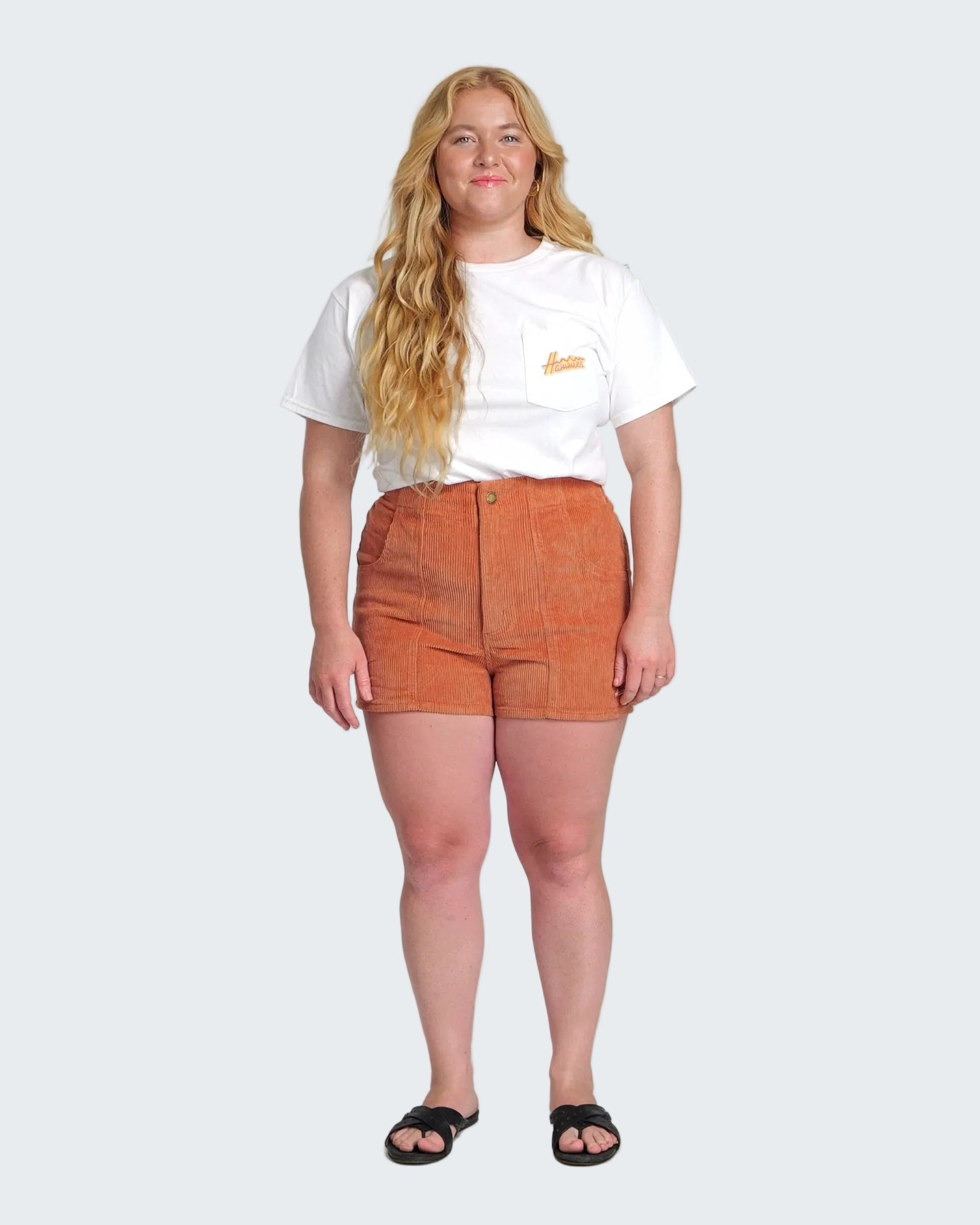 Person wearing a white t-shirt and orange shorts on a white background