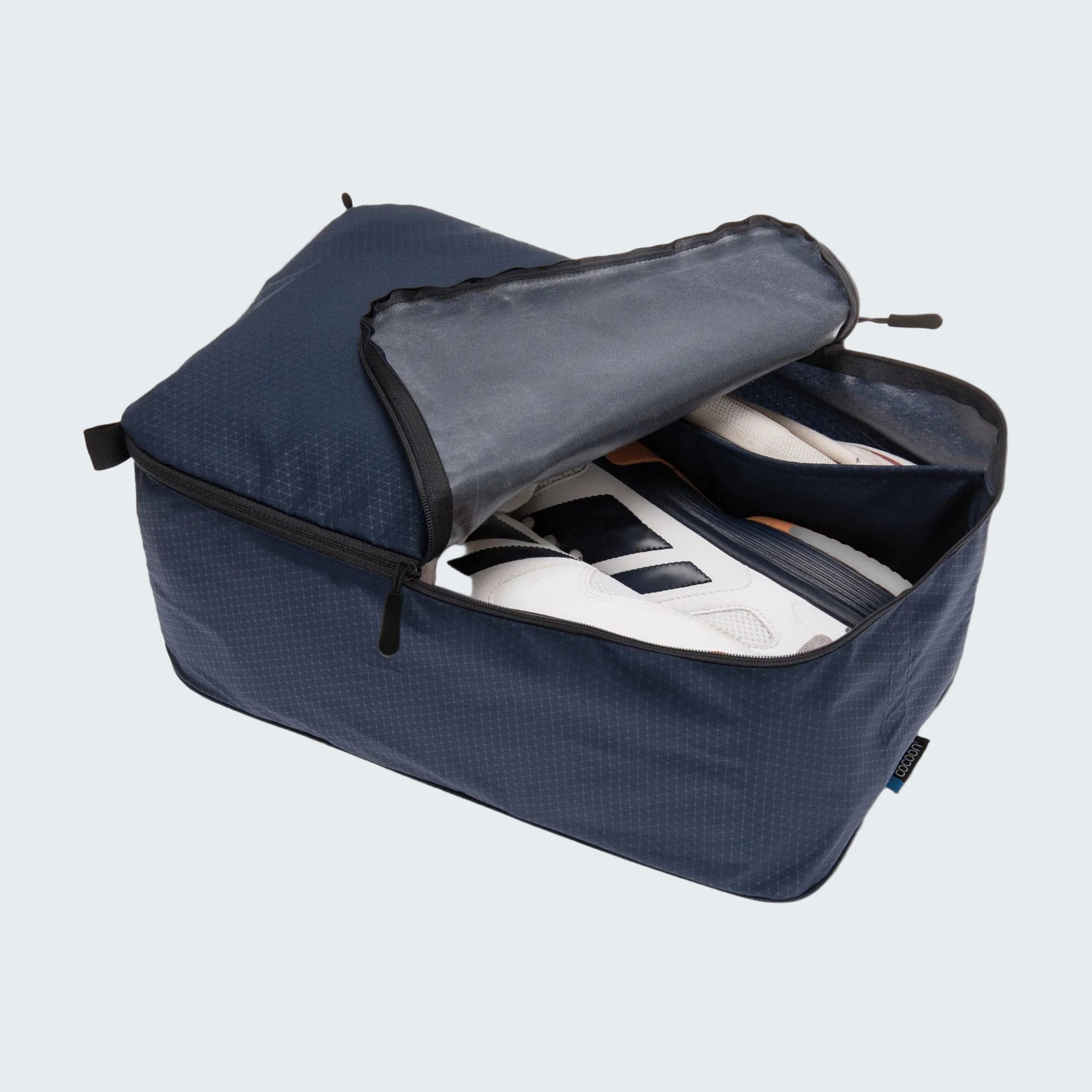 Blue travel shoe bag with a white shoe inside on a light gray background