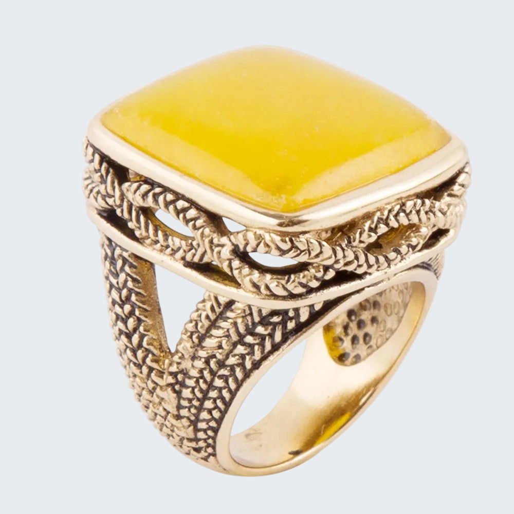 Gold ring with a yellow stone on a white background