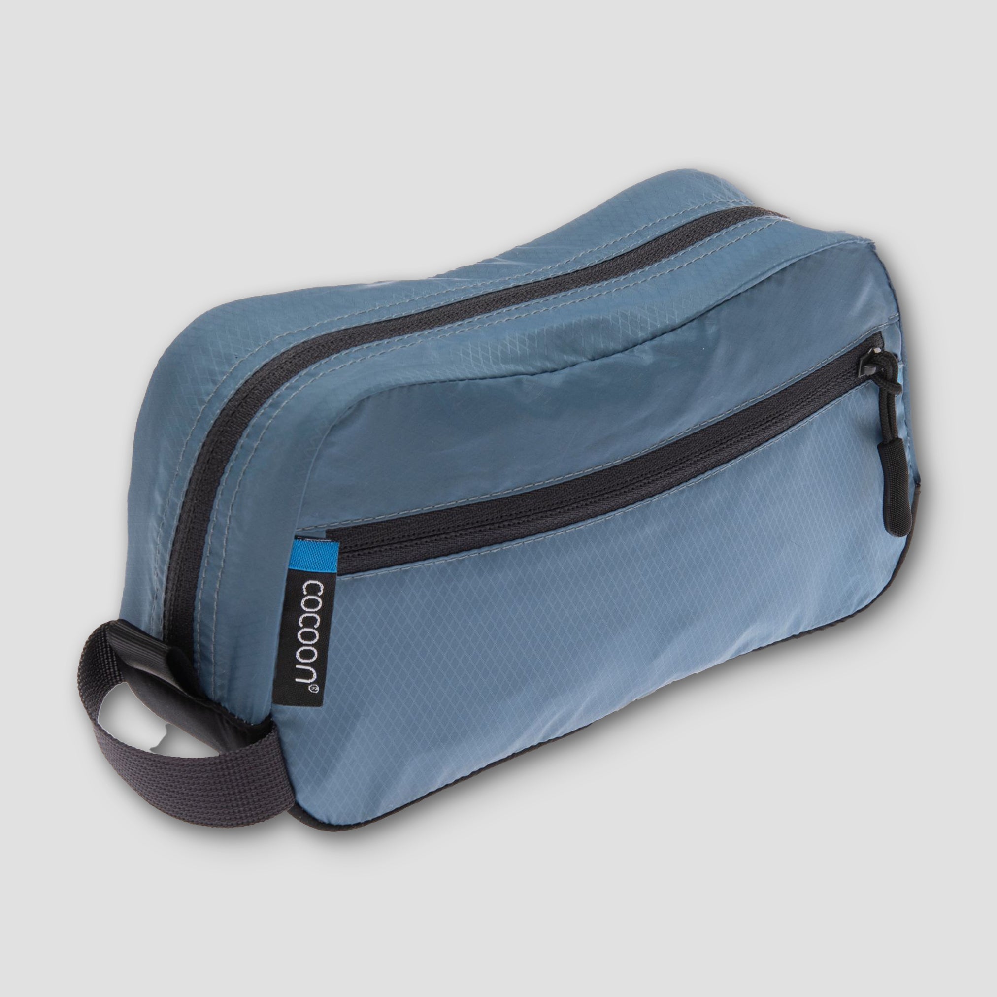 Blue toiletry bag with black zippers on a light gray background