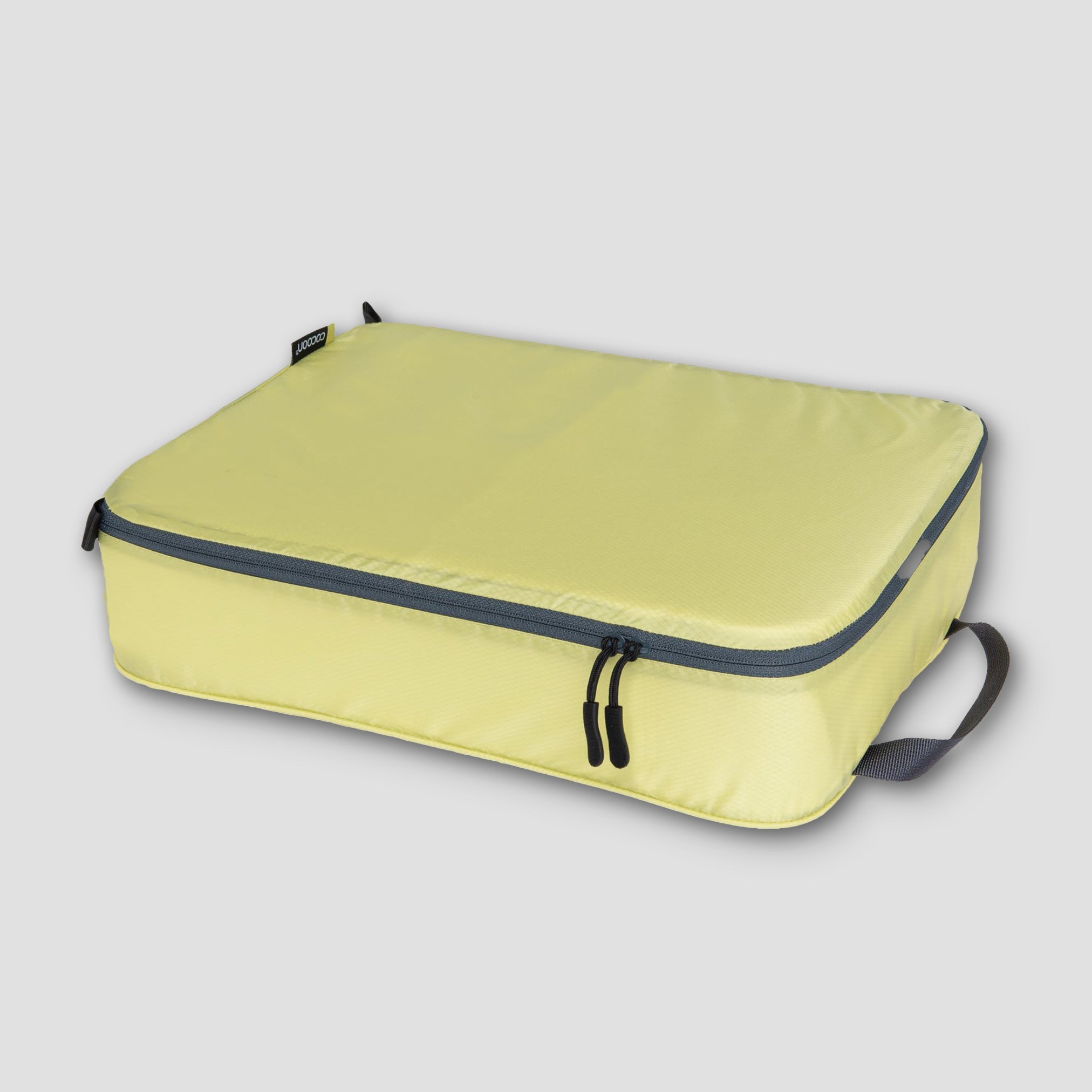 Yellow packing cube with gray zipper on a light gray background