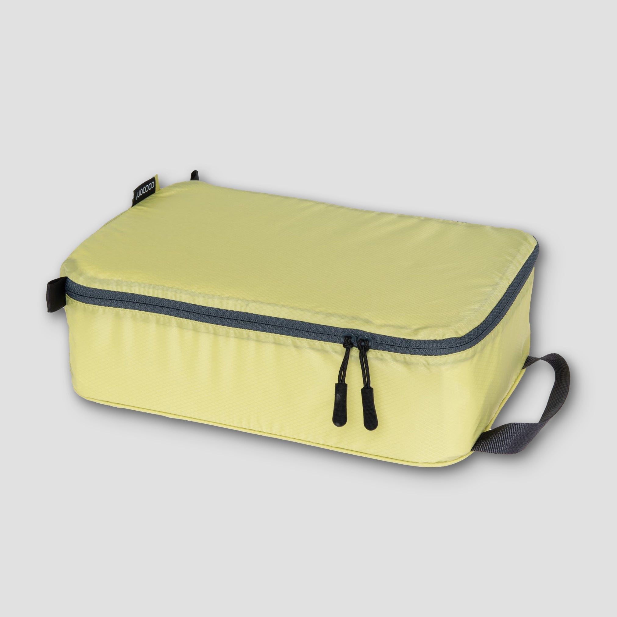 Yellow packing cube with black zippers on a light gray background