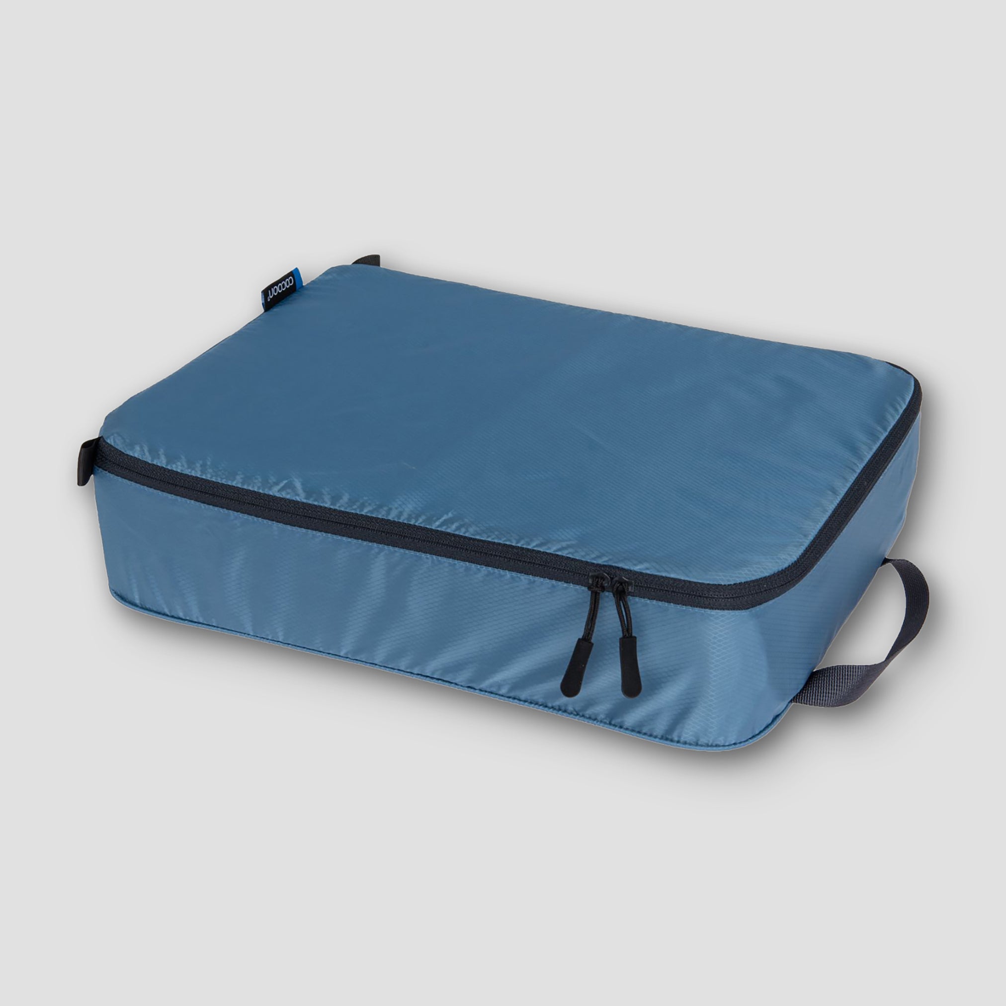 Blue packing cube with black zipper on a light gray background