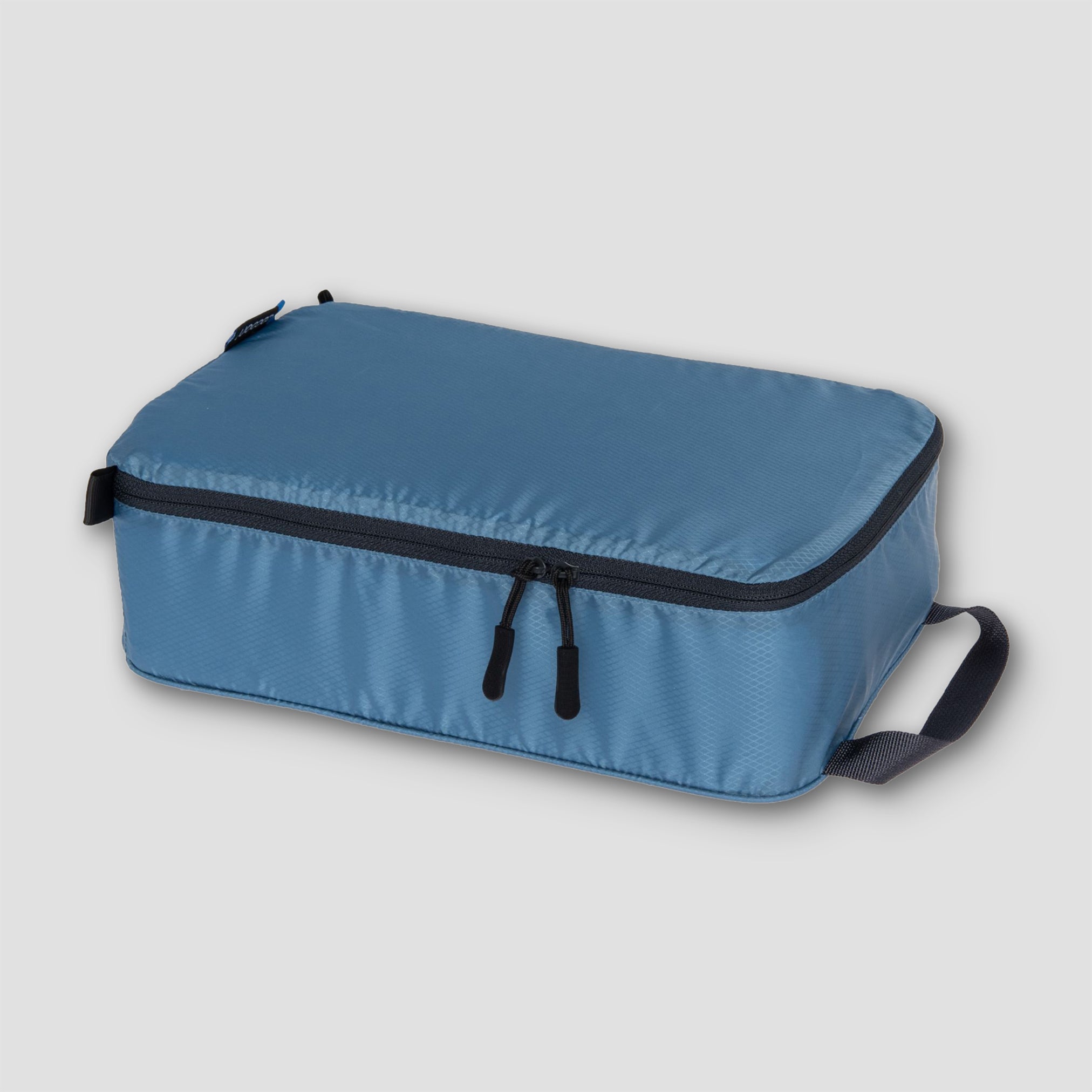Blue travel packing cube with black zippers on a light gray background