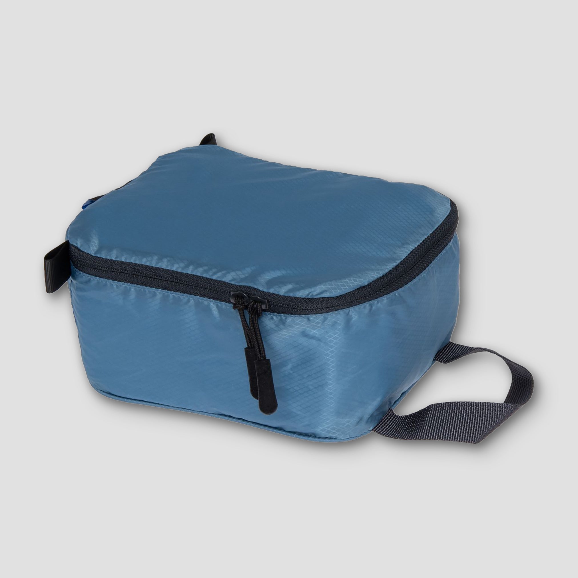 Blue packable bag with black zipper on a light gray background