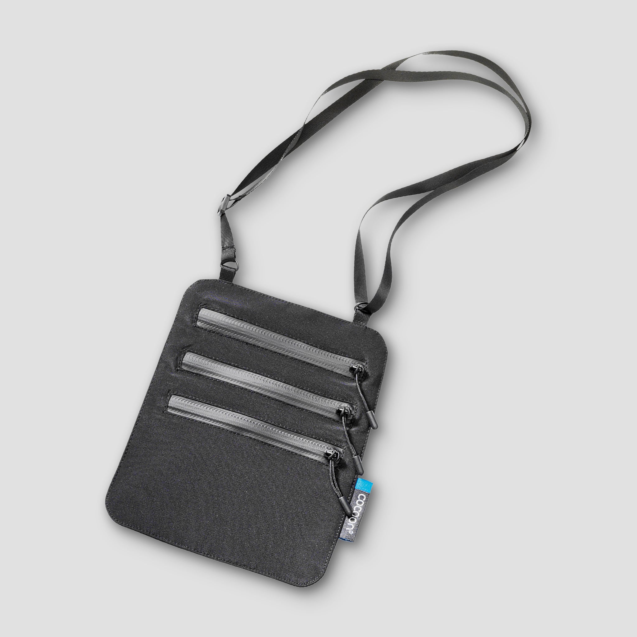 Gray crossbody bag with zippers on a light gray background