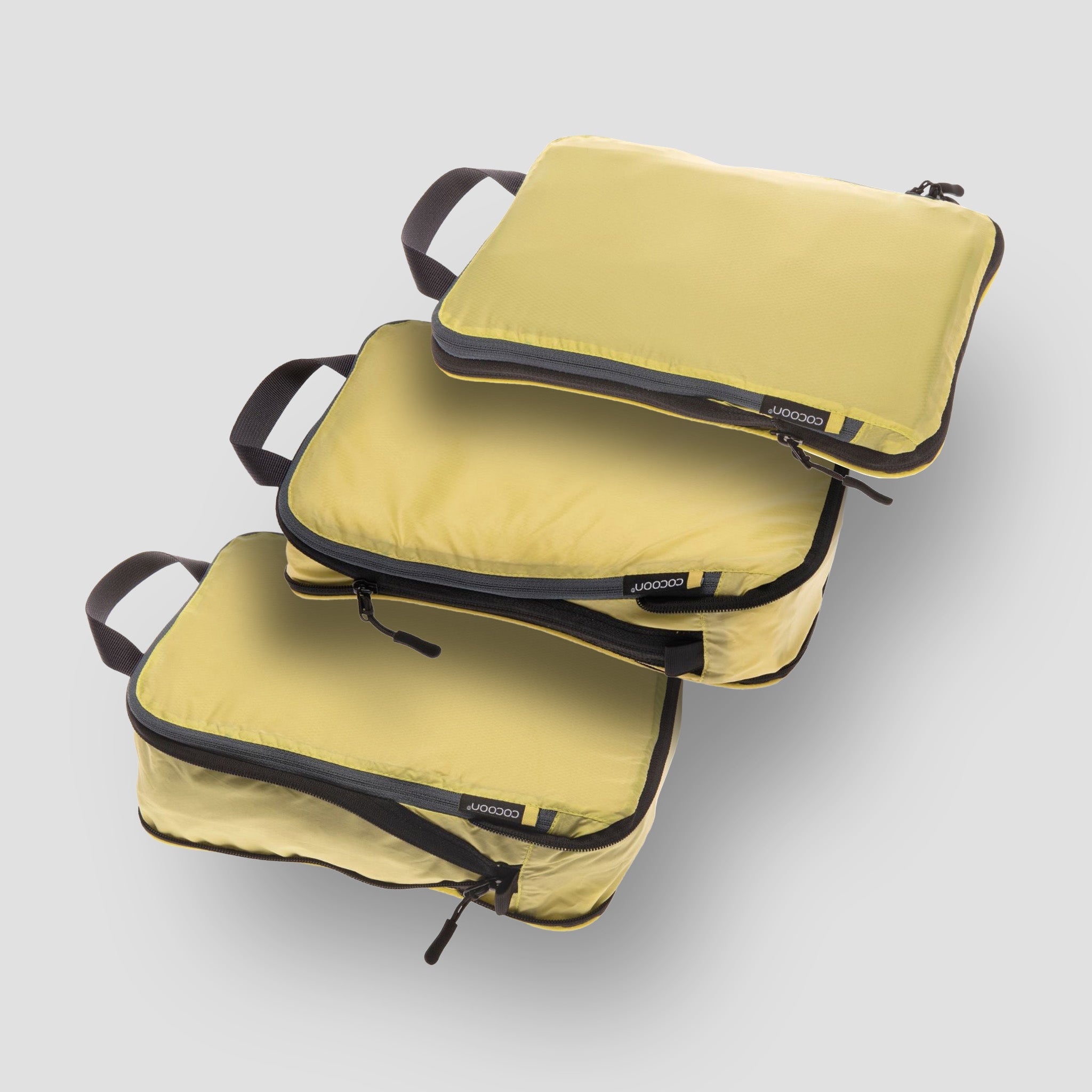 Three yellow packing cubes stacked on a light gray background