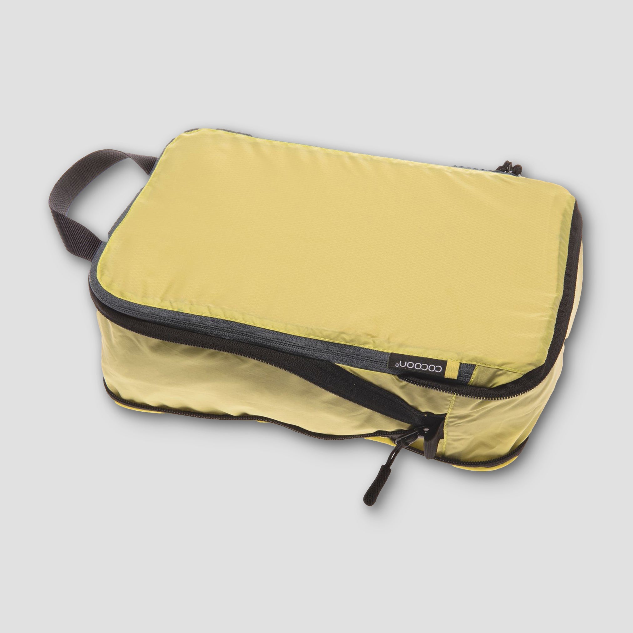 Yellow packing cube with black zipper on a light gray background