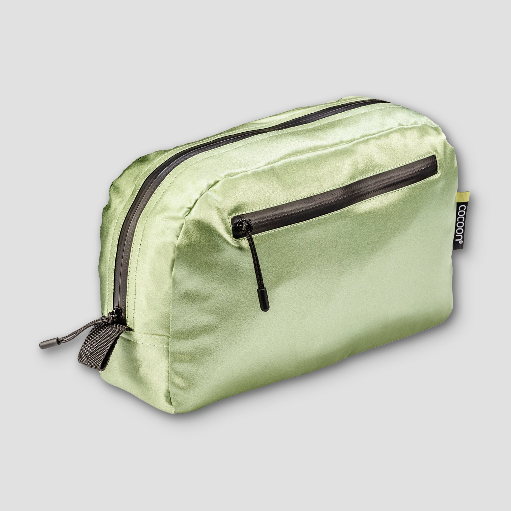 Light green toiletry bag with black zippers on a light gray background