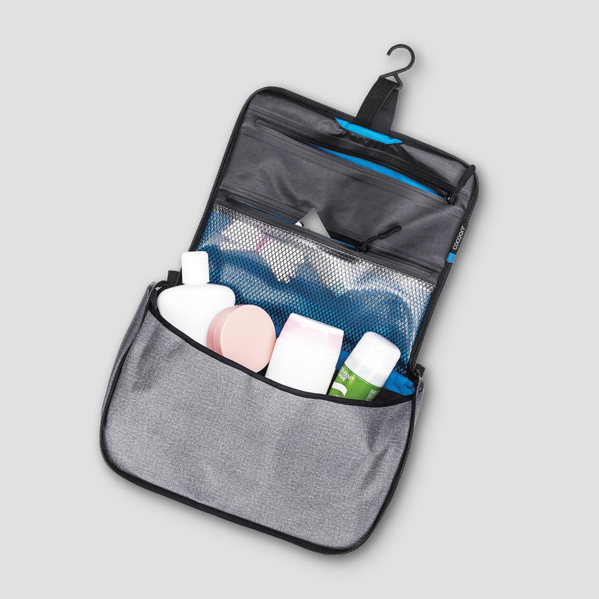 Gray toiletry bag with hanging hook containing skincare products on a light gray background