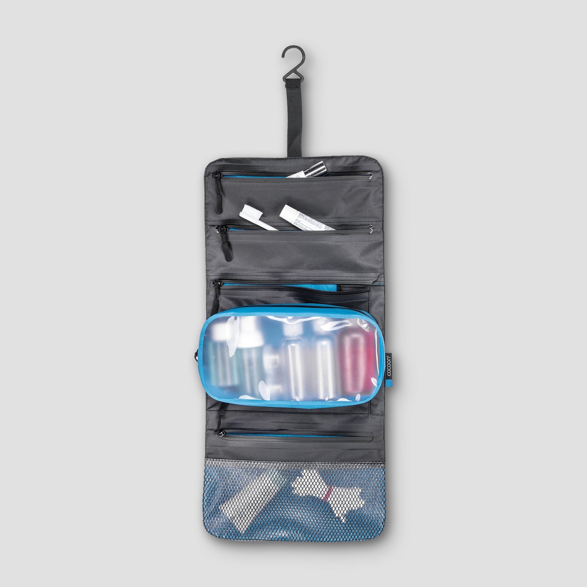 Travel toiletry bag with various compartments on a light gray background