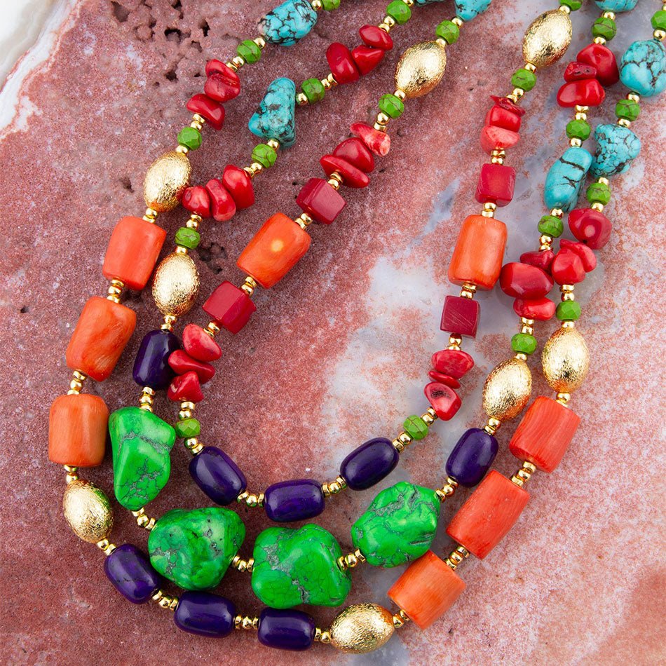 Colorful beaded necklace with red, green, blue, and gold beads on a textured surface.